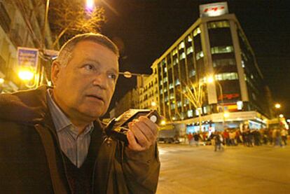 Un simpatizante del PP escuchaba anoche en la calle de Génova los resultados de las elecciones por la radio.