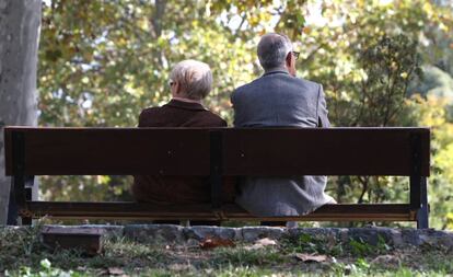 Dos ancianos, sentados en un banco de un parque público de Madrid.