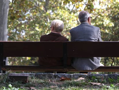 Dos ancianos, sentados en un banco de un parque público de Madrid.