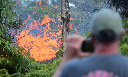 Un hombre fotografía una fuente de lava expulsada por una fisura en Leilani Estates, cerca de Pahoa, Hawái, el 4 de mayo de 2018. Más de 10.000 personas han sido evacuadas de sus casas tras la erupción del volcán Kilauea tras una serie de terremotos.