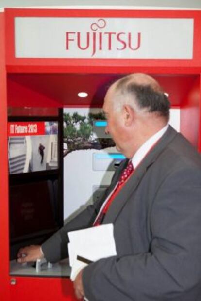 Un hombre prueba en Ifema un prototipo del cajero autom&aacute;tico que Fujitsu va a fabricar en Espa&ntilde;a para Europa.