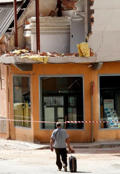 En la imagen, un vecino camina con su maleta por una calle del barrio de La Viñas de Lorca, afectado por el terremoto del 11 de mayo.