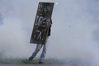 Manifestante se protege durante protesto em Brasília com uma placa pedindo a antecipação de eleições diretas para presidente. 