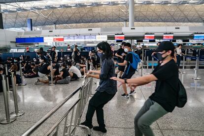 Varios manifestantes retiran unas vallas en la sala de embarque del aeropuerto internacional de Hong Kong, el 12 de agosto de 2019.