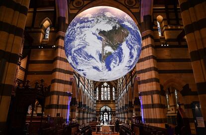 Visitantes de la catedral de San Pablo, en Melbourne, observan la obra 'Gaia', del artista Luke Jerram, un globo terráqueo gigante de siete metros de diámetro suspendido en el techo, donde rota.