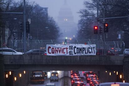 Una manta cuelga de un puente en North Capitol Street con el mensaje "Condena o sé cómplice", en el segundo día del juicio.