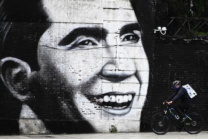 Un hombre con barbijo pasa con su bicicleta delante de un mural con el rostro de Carlos Gardel, en Buenos Aires, el 4 de mayo de 2020.