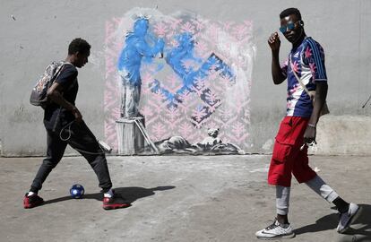Dos jóvenes pasan frente a una de las obras atribuidas a Banksy descubiertas esta semana en París, el 25 de junio de 2018. 