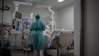 Una sanitaria visita a un enfermo ingresado en la Unidad de Cuidados Intensivos del Hospital de la Santa Creu i Sant Pau, Barcelona, en noviembre de 2020.
