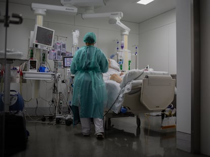Una sanitaria visita a un enfermo ingresado en la Unidad de Cuidados Intensivos del Hospital de la Santa Creu i Sant Pau, Barcelona, en noviembre de 2020.