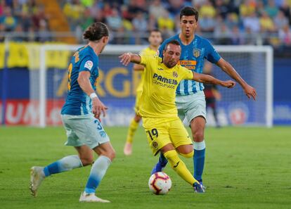 Santi Cazorla condece el balón. ante la oposición de dos contrarios