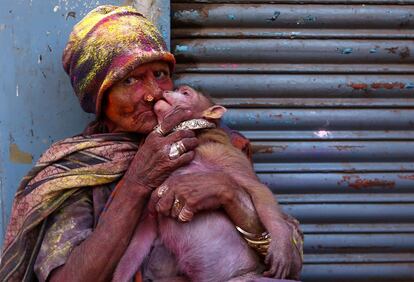 Una mujer embadurnada de colores besa a su mono durante la celebración del Holi en Chennai (India), el 2 de marzo de 2018.