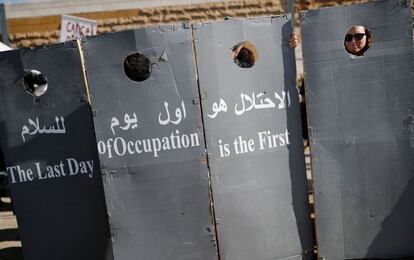 Un grupo de israelíes y palestinos miembros de la asociación "Combatentes por la Paz" portan varias pancartas que representan la polémica barrera de separación israelí durante una manifestación en una carretera cercana al pueblo de al-Khader, cerca de la ciudad bíblica de Belén (Cisjordania).