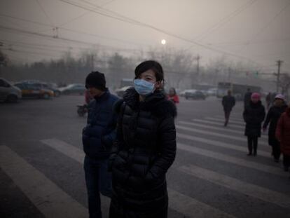 Una mujer con un cubrebocas cruza una calle en Pekín.
