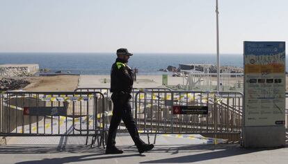 Un policía vigilando el acceso a la playa acordonada.