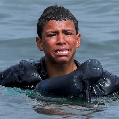 A Moroccan boy cries as he swims using bottles as a float, near the fence between the Spanish-Moroccan border, after thousands of migrants swam across the border, in Ceuta, Spain, May 19, 2021. Picture taken May 19, 2021. REUTERS/Jon Nazca