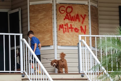 Noah Weibel and his dog Cookie climb the steps to their home as their family prepares for Hurricane Milton.