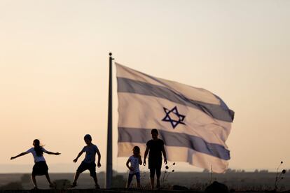 Niños israelíes juegan junto a una bandera israelí en la frontera de Israel con Siria, en los Altos del Golán, ocupados por Israel.