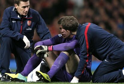 El portero del Arsenal, Szczesny, es atendido por los médicos después de un choque con Phil Jones.