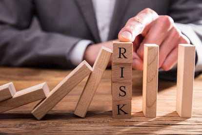 Businessperson's Finger Stopping Dominos From Falling