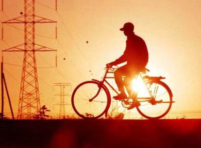 Un ciclista pasa junto a unas torres de alta tensión en las afueras de Nairobi, capital de Kenia.