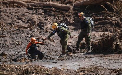 Membros da unidade de resgate israelense se aproximam para ajudar bombeiro na busca por vítimas.