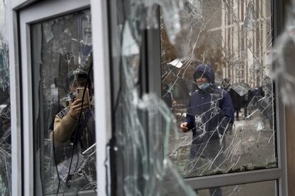 Un hombre toma una foto de las ventanas de un puesto de la policía dañadas por los manifestantes durante una protesta en Almaty, el día 5.