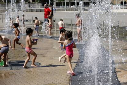 Numerosos niños se refrescan hoy en fuentes en las inmediaciones del Guggenheim de Bilbao.