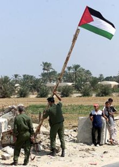 Dos policías colocan una bandera palestina cerca del asentamiento judío de Kfar Darom, en Gaza.