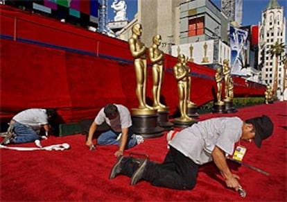 Unos operarios repasan los remates de la alfombra roja en el teatro Kodak.