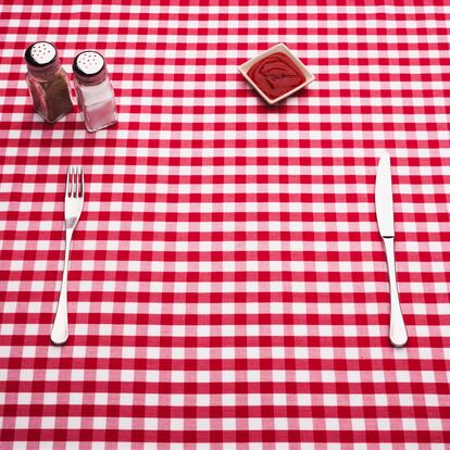 Table set with a bright tablecloth, cutlery and condiments