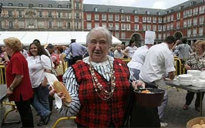 Una señora muestra su ración de cocido organizado en beneficio de la asociación Aldeas Infantiles SOS en la plaza Mayor.