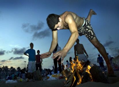 Un joven saltaba anoche una hoguera, en la playa de la Malva-rosa de Valencia.