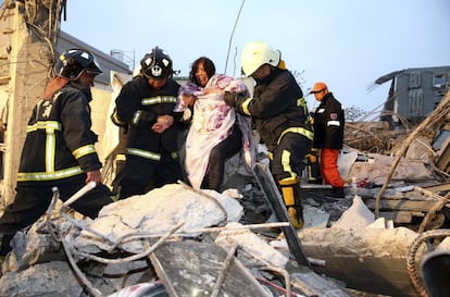 Hasta 30 personas continúan desaparecidas, según los medios locales. Entre los fallecidos se encuentra una bebé de apenas 10 días. En la imagen, personal de rescate ayudan a una mujer en el edificio derrumbado en Tainan (Taiwán).