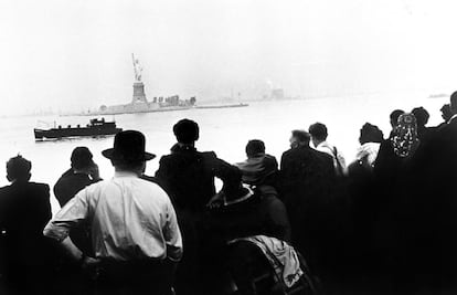 Un grupo de inmigrantes contempla la Estatua de la Libertad desde Ellis Island, 1910.