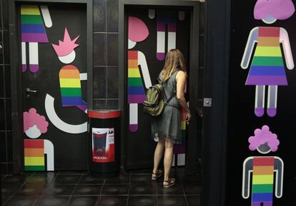 Una mujer entra en un baño del Mercado de San Antón decorado con motivo del World Pride.