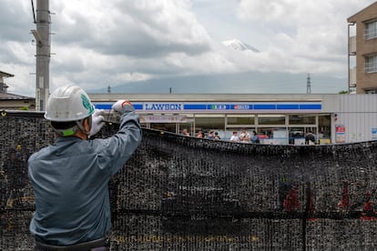 A worker installs a fence to block the view of Mount Fuji at Fujikawaguchiko in March.