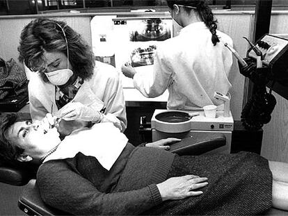 Una dentista examina la boca de una mujer.