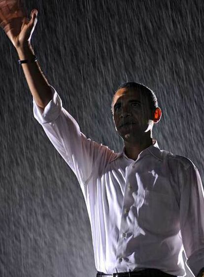 El candidato demócrata, Barak Obama, saluda bajo la lluvia al finalizar anoche un mitin electoral en Virginia.