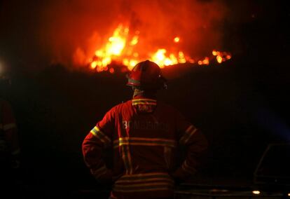 El fuego en torno a Pedrógão Grande, en el centro del país, debería estar controlado "hacia el final de la mañana", esperaba Vitor Vaz Pinto, responsable de protección civil, gracias al trabajo de los 1.150 bomberos y cerca de 400 vehículos que seguían movilizados. En la imagen, un bombero contempla las llamas del incendio forestal en Carvalho, el 19 de junio de 2017.