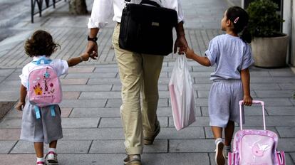 Un padre lleva de la mano a sus hijas camino del colegio, en el primer día de clase, en Madrid.