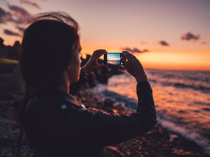 Una mujer utiliza la cámara de su móvil para fotografiar el atardecer.