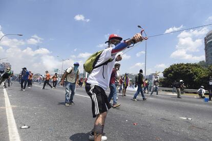 Un joven opositor del presidente venezolano lanza una piedra contra la policía.