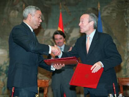 Colin Powell y Josep Piqué se dan la mano, en presencia de Aznar, tras firmar el nuevo convenio.