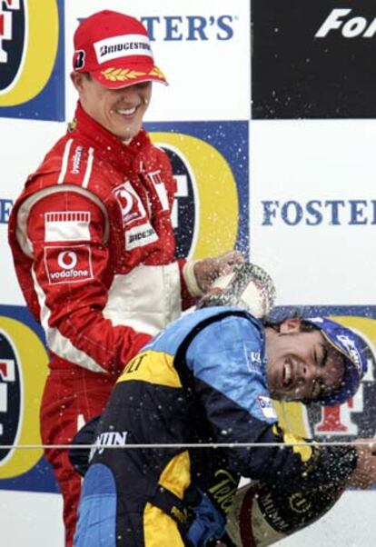 Michael Schumacher y Fernando Alonso se rocían con champaña en el podio de Silverstone.