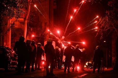 Los oficiales de policía observan cómo los fuegos artificiales lanzados por los manifestantes explotan frente a ellos durante una manifestación en Atenas, el 6 de diciembre de 2018, cuando se cumplió el décimo aniversario del asesinato fatal de un adolescente que provocó importantes disturbios en Grecia en 2008.