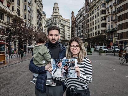 Adrián Martínez y Tatiana Mendoza junto a su hijo, en Valencia, tras volver de Ucrania. Ambos sostienen una foto con una imagen de su vida en el país.