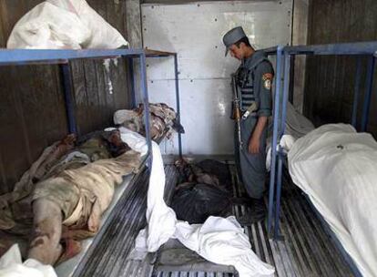 Un policía afgano mira los cuerpos de los talibanes muertos en combate contra las fuerzas de la OTAN en la provincia de Helmand.
