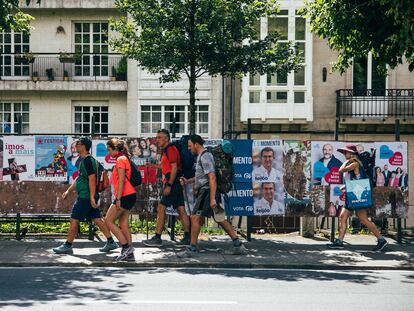 Un grupo de peregrinos del Camino de Santiago pasa frente a unos carteles electorales en Galicia en julio.