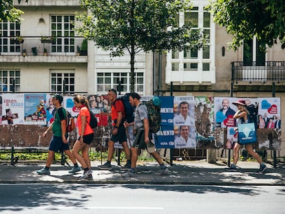 Un grupo de peregrinos del Camino de Santiago pasa frente a unos carteles electorales en Galicia en julio.